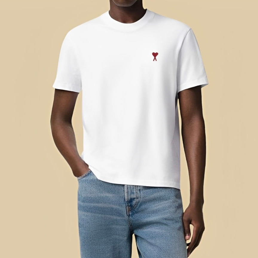 Man wearing an Ami Paris white t-shirt with a red heart logo on a beige background