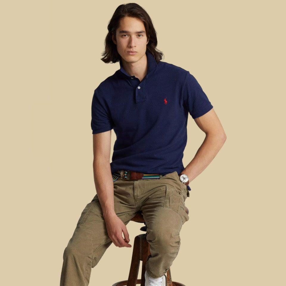 Man wearing Ralph Lauren navy blue polo shirt with a red logo on a beige background